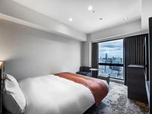a bedroom with a bed and a large window at DEL style Osaka-Shinsaibashi by Daiwa Roynet Hotel in Osaka