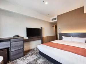 a hotel room with a bed and a flat screen tv at DEL style Osaka-Shinsaibashi by Daiwa Roynet Hotel in Osaka
