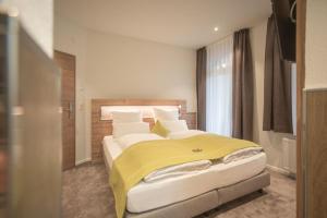 a bedroom with a large bed with a yellow blanket at Hotel dasZimmermann in Todtmoos