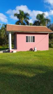 una pequeña casa rosa con un patio de césped en Mini Casa Chácara Zulin's - AMOR E ACONCHEGO en Pontal do Paraná