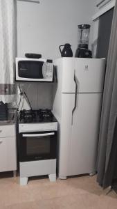 a kitchen with a microwave and a stove and a refrigerator at Mini Casa Chácara Zulin's - AMOR E ACONCHEGO in Pontal do Paraná