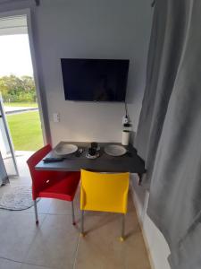 a dining table with two chairs and a table with plates on it at Mini Casa Chácara Zulin's - AMOR E ACONCHEGO in Pontal do Paraná