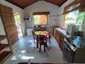 uma cozinha com uma mesa e uma sala de jantar em Chalé da Barra - Loft em Maraú