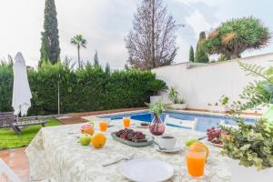 una mesa con comida y fruta junto a una piscina en ETELVILLA, en El Puerto de Santa María