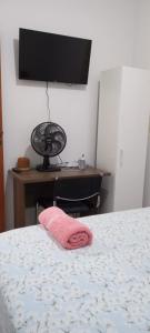 um quarto com uma cama e uma secretária com uma toalha rosa em Quarto Hokkaido na Sakura House em Indaiatuba