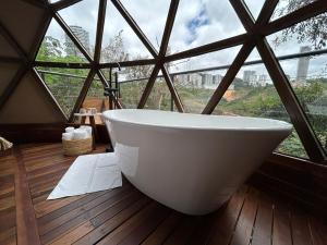 a bath tub in a room with a large window at Domo Vila da Serra in Nova Lima