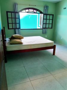 Bett in einem Zimmer mit Fenster und einem Bett mit Kissen in der Unterkunft casa do serramar in Rio das Ostras
