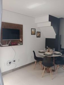 a dining room with a table and chairs and a tv at Linda Casa 2 no Sossego da Praia in Balneário Camboriú