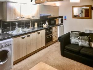 a kitchen with a sink and a couch in a room at Elseghyll Barn in Melmerby