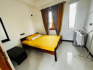 ein Schlafzimmer mit einem Bett mit gelber Bettwäsche und einem Fenster in der Unterkunft villa24.trinco in Trincomalee