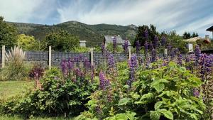 un jardín con flores púrpuras frente a una valla en CASITA DE ANELÉ en San Carlos de Bariloche