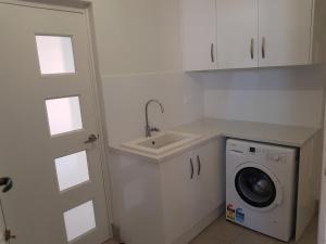 uma cozinha com um lavatório e uma máquina de lavar roupa em Spacious self contained unit - short walk to Grange Jetty em Grange
