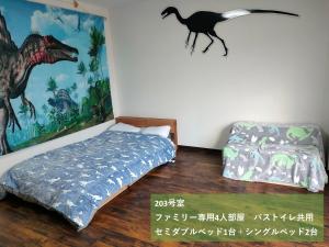 勝山市にある11月フルリフォーム 12月オープン恐竜一色ゲストハウスDinosaur Guesthouseのベッドルーム1室(壁に恐竜の壁画、ベッド1台付)