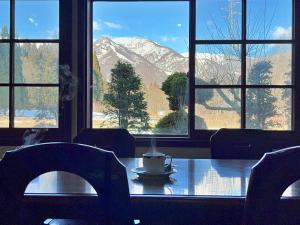 a table with a cup of coffee sitting on it in front of windows at ロッヂ秀岳 in Chikuni