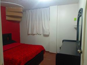 1 dormitorio con cama roja y ventana en Acogedor apartamento en Píllaro, en Píllaro
