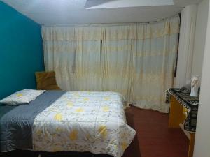 1 dormitorio con 1 cama y una ventana con cortinas en Acogedor apartamento en Píllaro, en Píllaro