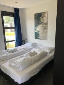2 weiße Betten in einem Zimmer mit Fenster in der Unterkunft Enkhuizer Strand Chalet Strandpanorama Zweite Reihe mit Zaun Hausnr 203 in Enkhuizen
