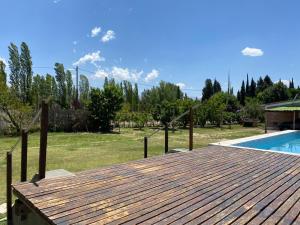 una terraza de madera junto a una piscina en Cabañas Vista Andes IV en Luján de Cuyo