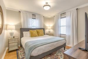 a bedroom with a large bed with two tables and two windows at OneCozyPlace Tulsa - King Bed Expo, TU, Downtown in Tulsa