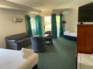 a hotel room with a bed and a couch and a table at Seaside Garden Retreat Accommodation in Wamberal