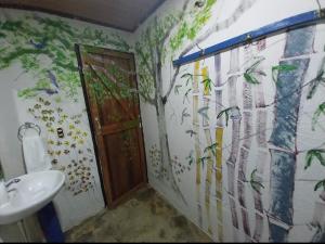 a bathroom with a sink and a wall with a mural at Happy Monkeys in Puerto Jiménez