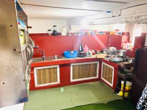 una pequeña cocina con paredes rojas y lavabo. en Dulal’s Homestay en Godāvari