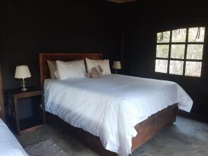 a bedroom with a large white bed with two windows at VlakkiesKraal Bosbok Camp in Bela-Bela