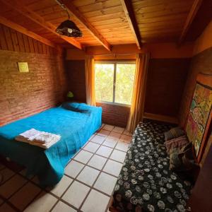 Un dormitorio con una cama azul y una ventana en June en el Uritorco en Capilla del Monte