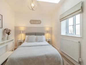 a white bedroom with a bed and two tables at The Nest in Bempton