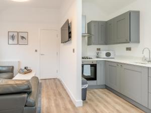 a kitchen with white cabinets and a living room with a couch at The Nest in Bempton
