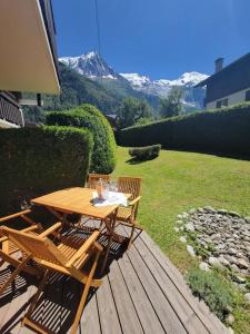 een houten tafel en stoelen op een terras met een berg bij Chamonix Garden Flat with a View of Mont-Blanc in Chamonix-Mont-Blanc
