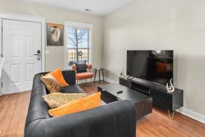 ein Wohnzimmer mit einem schwarzen Sofa und einem Flachbild-TV in der Unterkunft Affordable 1-BR by DMC Detroit in Detroit