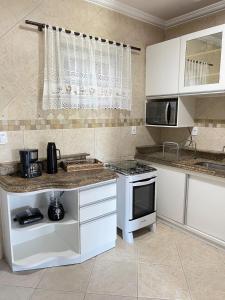 uma cozinha com armários brancos e um forno com placa de fogão em Ótima Casa com Piscina, Sauna e Churrasqueira em Cabo Frio