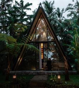 a person sitting in front of a glass house at Delta Casa Ubud- Tiny Villas in Bali's Jungles in Gianyar