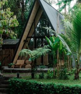 a small house with a triangular roof in a garden at Delta Casa Ubud- Tiny Villas in Bali's Jungles in Gianyar