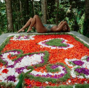 een vrouw die op een bloementuin ligt bij Delta Casa Ubud- Tiny Villas in Bali's Jungles in Gianyar