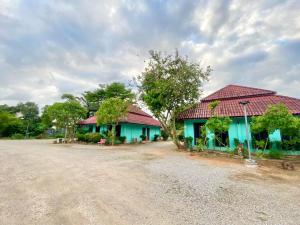 Thungtako Resort في Ban Samnak Pling: بيت ازرق بسقف احمر بجانب طريق ترابي