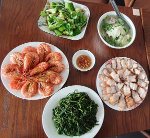 uma mesa com pratos de camarão e legumes em Xan hotel Phu Quoc em Duong Dong