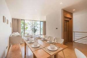 uma sala de jantar com uma mesa de madeira e cadeiras brancas em Marbella Beachfront Pattaya 3BR em Bang Lamung
