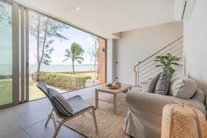 uma sala de estar com um sofá e vista para o oceano em Marbella Beachfront Pattaya 3BR em Bang Lamung
