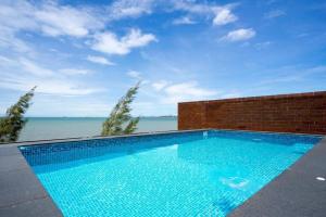 a swimming pool with a view of the water at Marbella Beachfront Pattaya 3BR in Bang Lamung