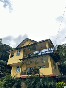 un bâtiment jaune avec un panneau en haut dans l'établissement Highlanders Garden Guesthouse at Arundina Cameron Highlands, à Cameron Highlands