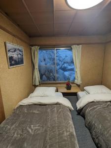 two beds in a room with a window at 白馬の黒馬　DarkHorse @Hakuba in Hakuba