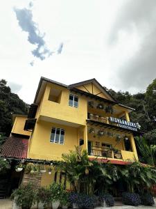 un bâtiment jaune avec un panneau sur lequel figure un panneau dans l'établissement Highlanders Garden Guesthouse at Arundina Cameron Highlands, à Cameron Highlands