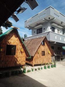 Kua's Pad Batangas Room في ليان: مبنى كبير أمامه منزل خشبي