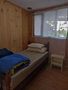 Dormitorio pequeño con cama y ventana en Gran casa a orillas del lago, en Licán Ray