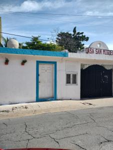ein weißes Gebäude mit blauer Tür auf einer Straße in der Unterkunft Casa San Miguel 1 in Cozumel