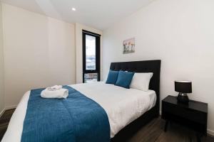 1 dormitorio con 1 cama grande con manta azul en Cozy Box Hill Apartment, en Box Hill