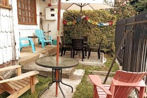 a patio with a table and chairs and an umbrella at Casa completa para 6 personas centro Puerto Montt, 700 metros estatua enamorados in Puerto Montt
