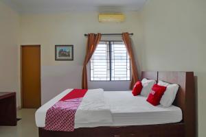 een slaapkamer met een bed met rode en roze kussens bij OYO 92314 De Coco Guesthouse in Medan